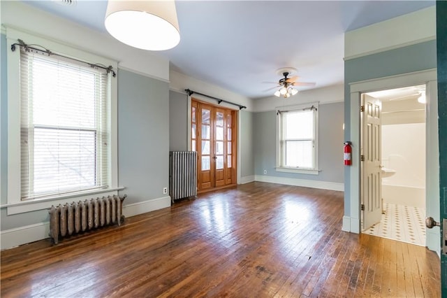 unfurnished room featuring ceiling fan, radiator heating unit, baseboards, and wood-type flooring