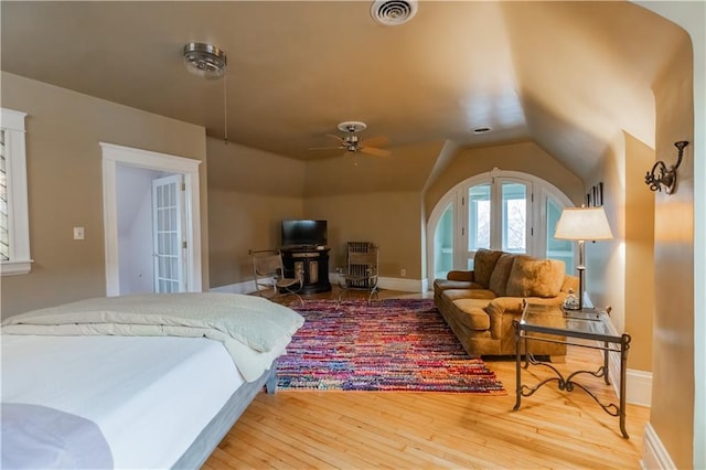 bedroom with lofted ceiling, hardwood / wood-style flooring, visible vents, and baseboards