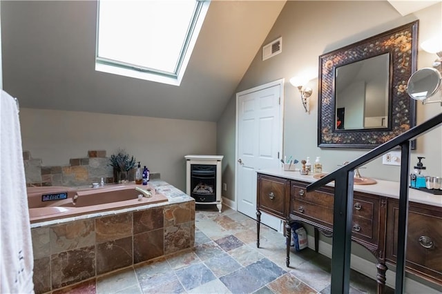 bathroom featuring lofted ceiling with skylight, visible vents, a garden tub, and vanity