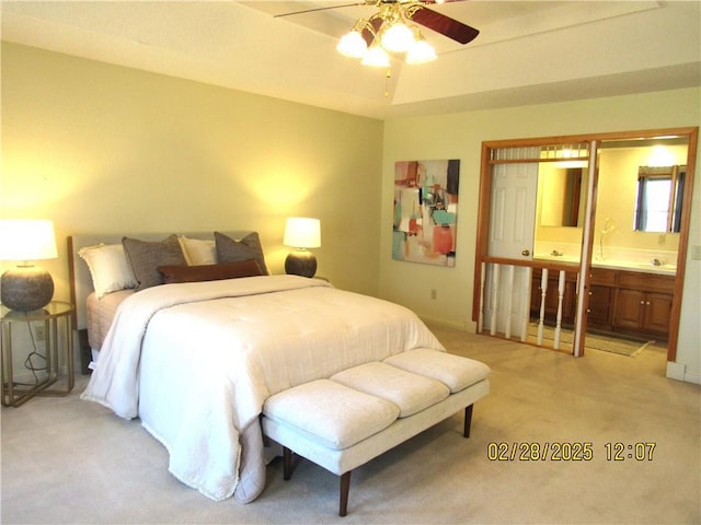 bedroom with light carpet, a raised ceiling, a ceiling fan, and ensuite bathroom