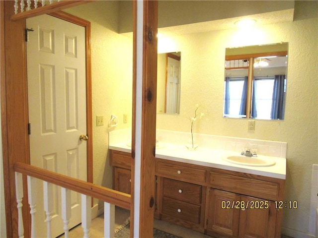 bathroom with a textured wall and vanity