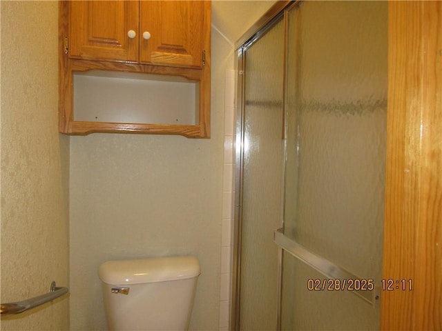 bathroom with toilet and an enclosed shower