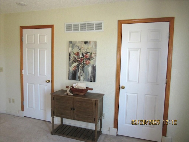 hall featuring carpet floors and visible vents