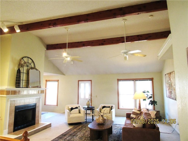 living room featuring lofted ceiling with beams, carpet floors, a ceiling fan, and a tile fireplace