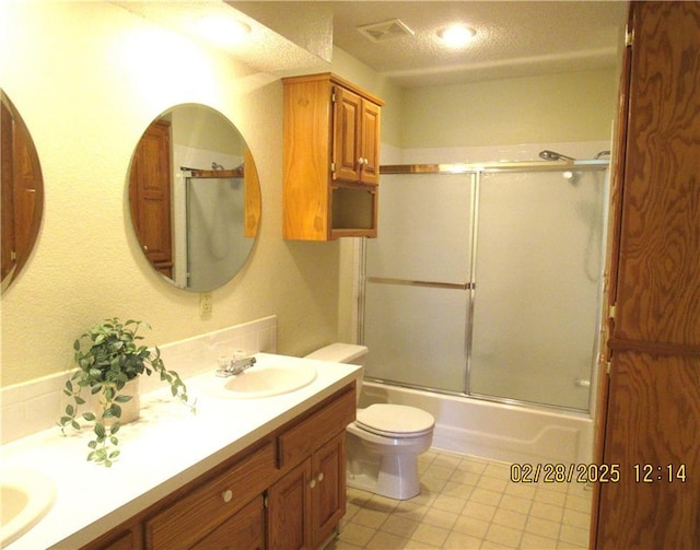 bathroom with double vanity, visible vents, toilet, enclosed tub / shower combo, and a sink