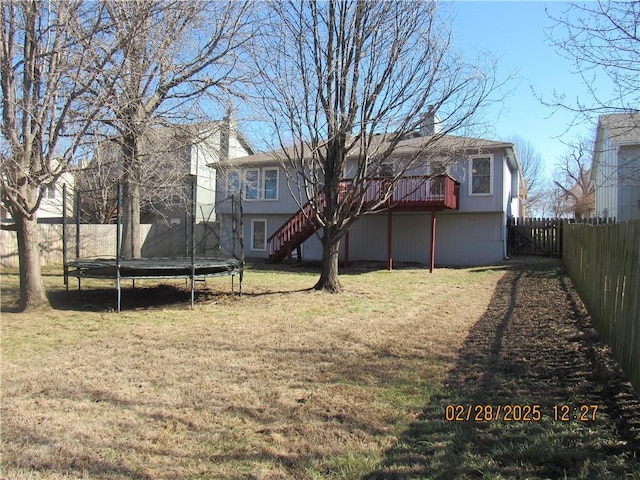 exterior space featuring a fenced backyard, a trampoline, stairway, and a lawn