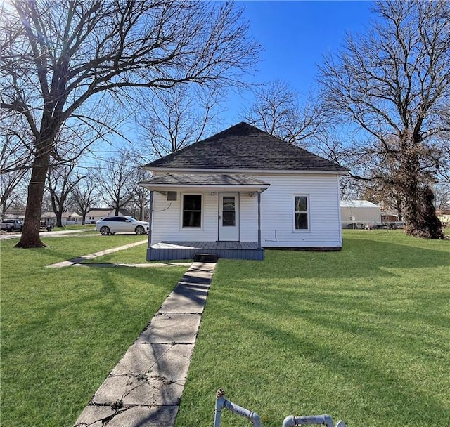 bungalow-style house with a porch, roof with shingles, and a front yard