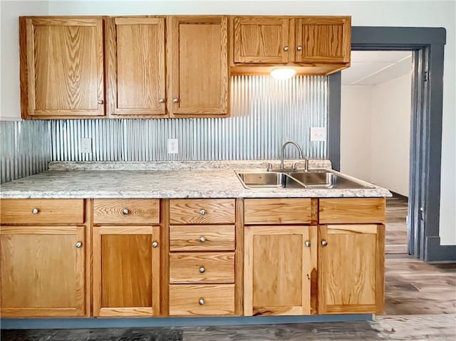 kitchen with light stone counters, a sink, and wood finished floors