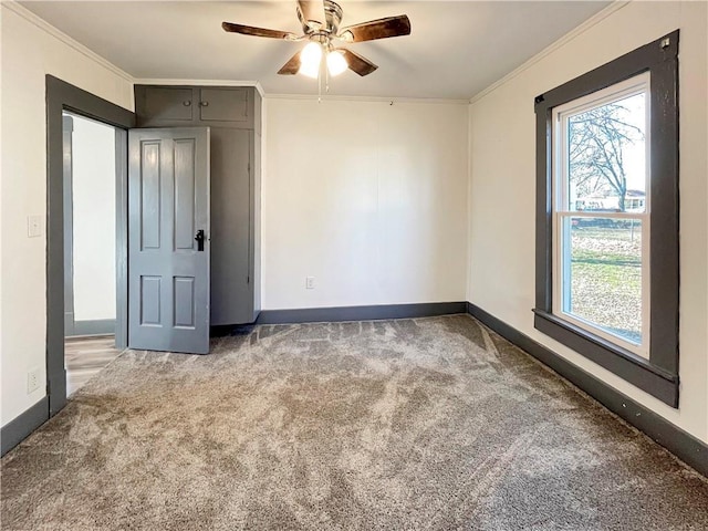 spare room featuring ornamental molding, a wealth of natural light, carpet flooring, and baseboards