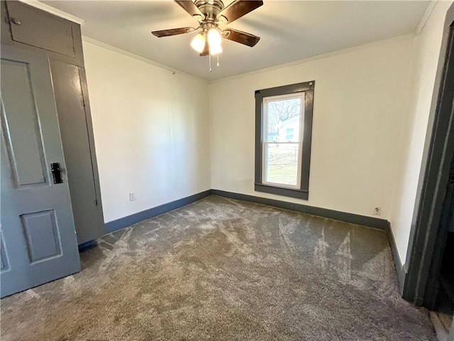 unfurnished room with ornamental molding, dark carpet, baseboards, and a ceiling fan