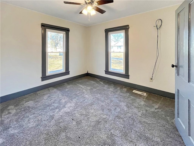 spare room featuring visible vents, dark carpet, baseboards, and ceiling fan