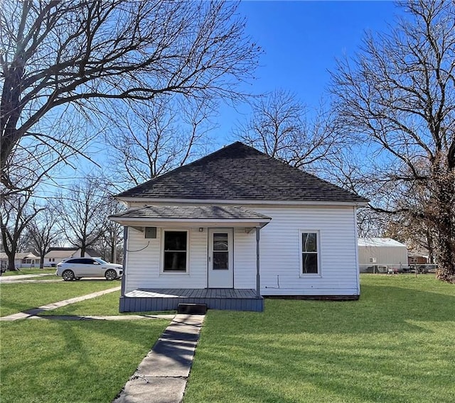 bungalow with a porch, a front yard, and roof with shingles