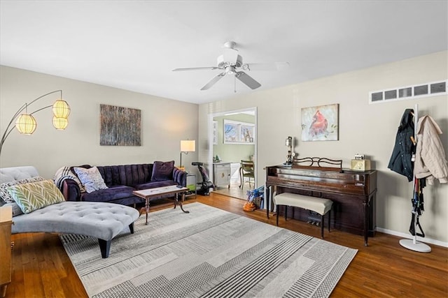 living area featuring baseboards, visible vents, wood finished floors, and ceiling fan