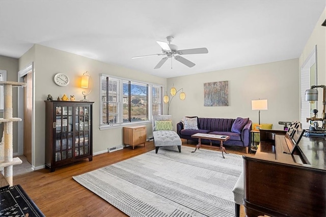 living area featuring wood finished floors, a ceiling fan, and baseboards