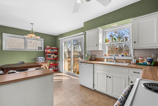 kitchen with tasteful backsplash, butcher block counters, white cabinets, dishwasher, and a sink