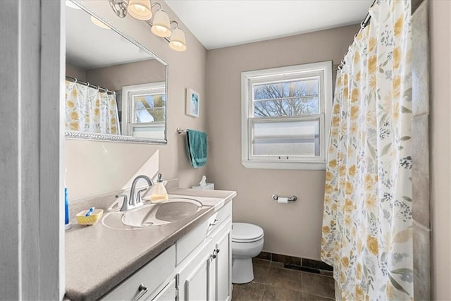 full bath with toilet, tile patterned floors, a wealth of natural light, and vanity