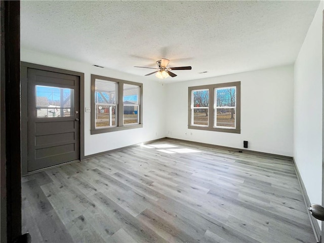 entrance foyer with a textured ceiling, wood finished floors, visible vents, and baseboards