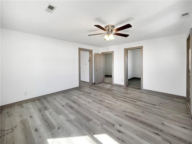 unfurnished bedroom with baseboards, ceiling fan, visible vents, and light wood-style floors