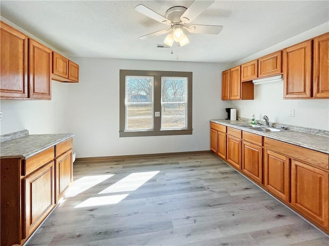 kitchen featuring light wood finished floors, light countertops, and a sink