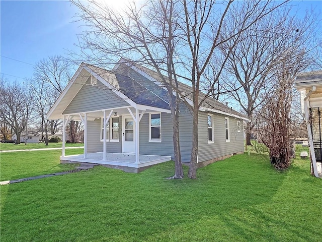 exterior space featuring covered porch, roof with shingles, and a yard