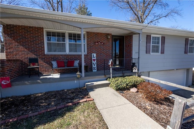 property entrance with a porch, an attached garage, and brick siding