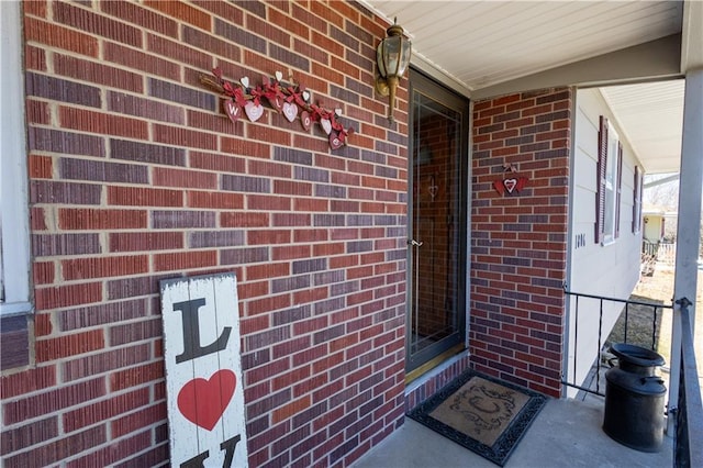 entrance to property with a porch and brick siding