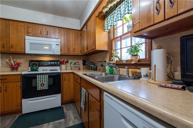 kitchen with brown cabinets, a sink, white appliances, light countertops, and decorative backsplash