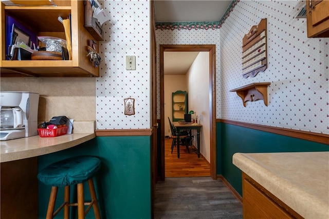 kitchen featuring wallpapered walls, open shelves, a kitchen breakfast bar, and dark wood finished floors