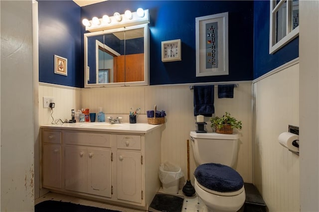 half bath with vanity, toilet, and wainscoting