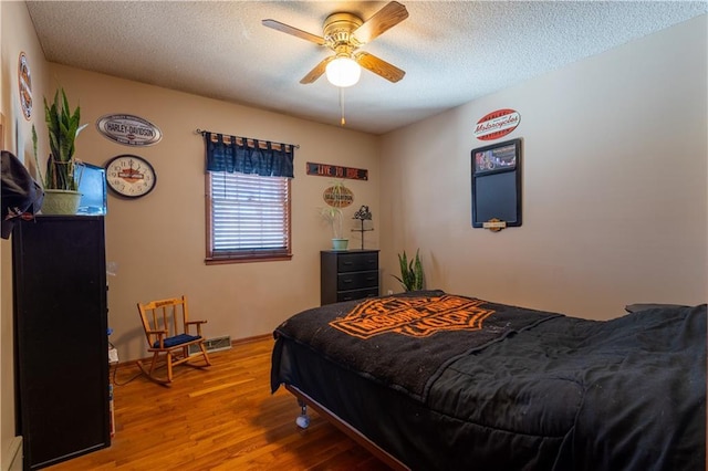 bedroom with ceiling fan, a textured ceiling, and wood finished floors