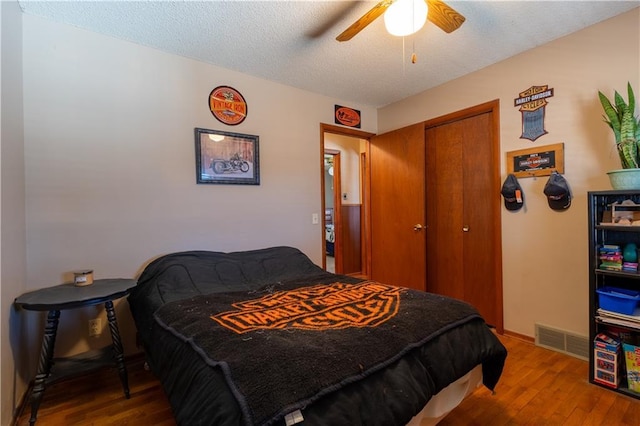 bedroom with visible vents, a textured ceiling, a closet, and wood finished floors