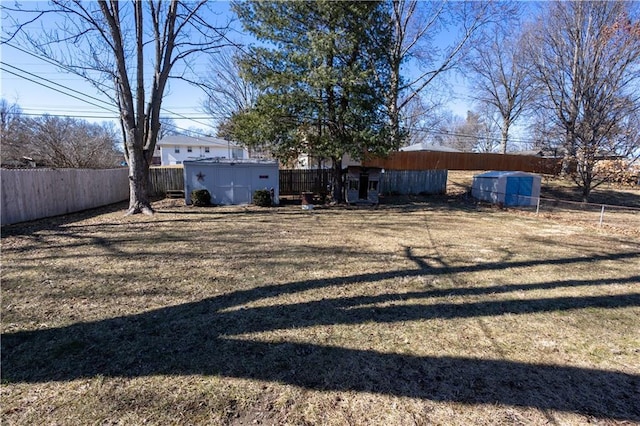 view of yard featuring an outdoor structure, a fenced backyard, and a shed