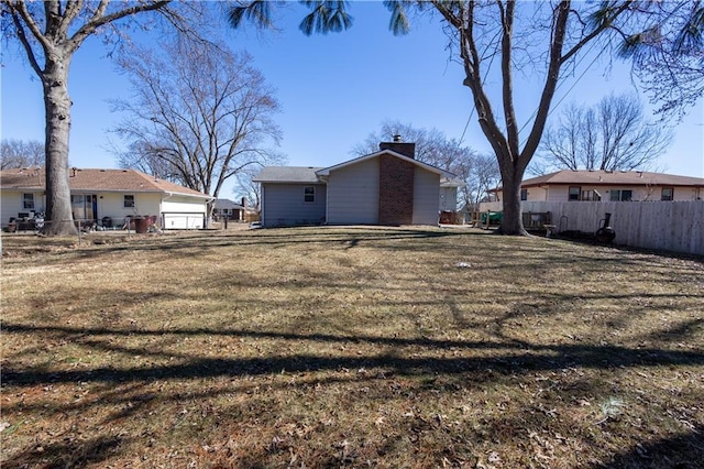 exterior space with a lawn, a chimney, and fence