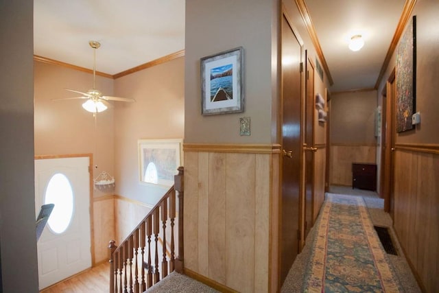 entrance foyer with a ceiling fan, wooden walls, ornamental molding, and visible vents