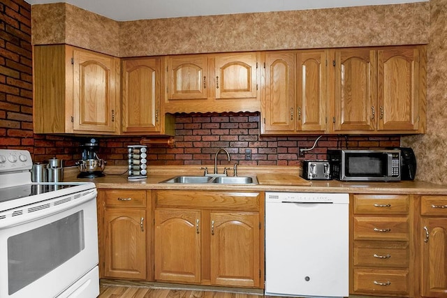kitchen with light countertops, brown cabinets, a sink, and white appliances