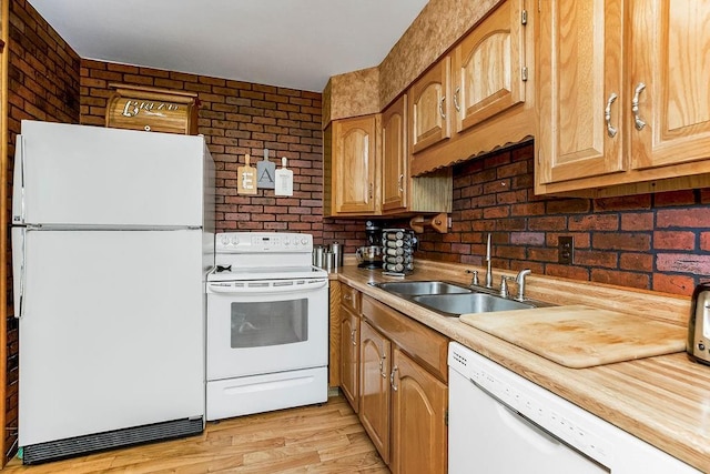 kitchen with brick wall, a sink, light countertops, white appliances, and light wood-style floors