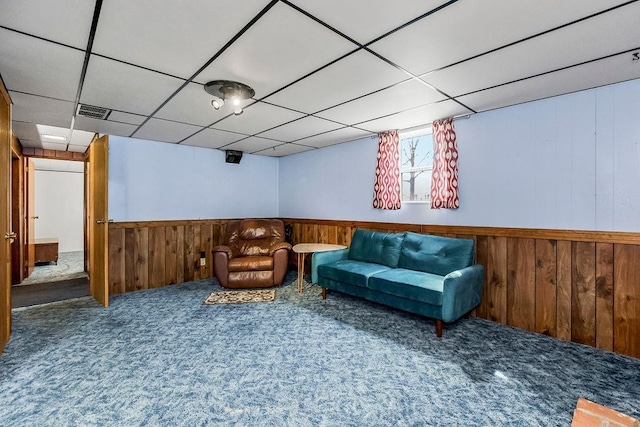 sitting room with visible vents, carpet flooring, wainscoting, wood walls, and a drop ceiling