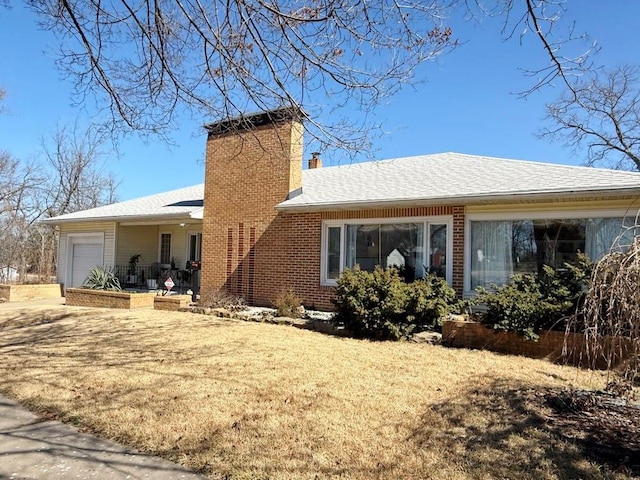 exterior space featuring a lawn, a chimney, roof with shingles, an attached garage, and brick siding