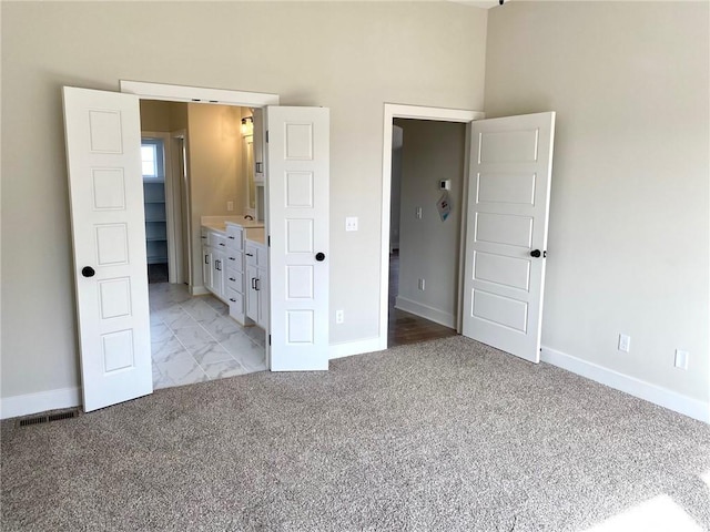 unfurnished bedroom featuring light colored carpet, a sink, visible vents, baseboards, and marble finish floor