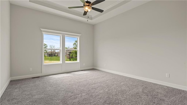 unfurnished room with visible vents, baseboards, a raised ceiling, ceiling fan, and carpet