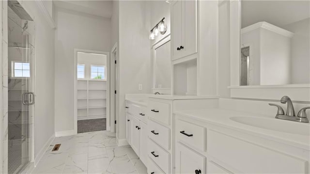 full bath featuring double vanity, a marble finish shower, baseboards, marble finish floor, and a sink