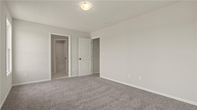 unfurnished bedroom with ensuite bath, carpet flooring, and baseboards