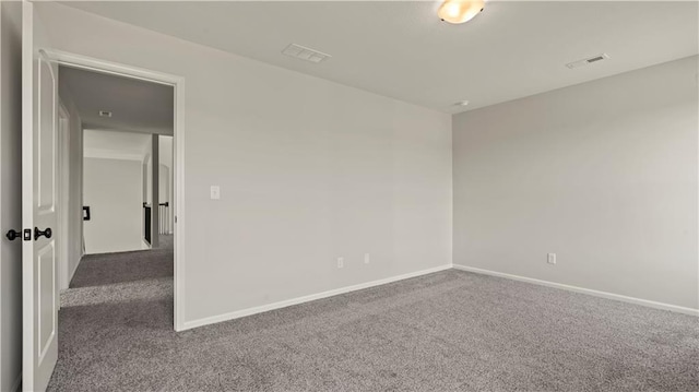 spare room with carpet flooring, visible vents, and baseboards