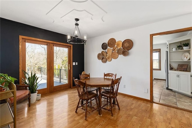 dining space featuring baseboards, light wood finished floors, and a chandelier