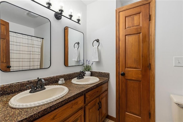 full bath featuring double vanity, toilet, and a sink