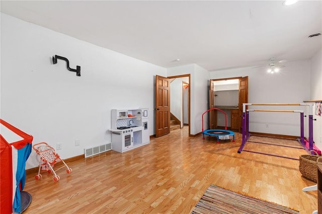 recreation room with visible vents, a ceiling fan, baseboards, and wood finished floors