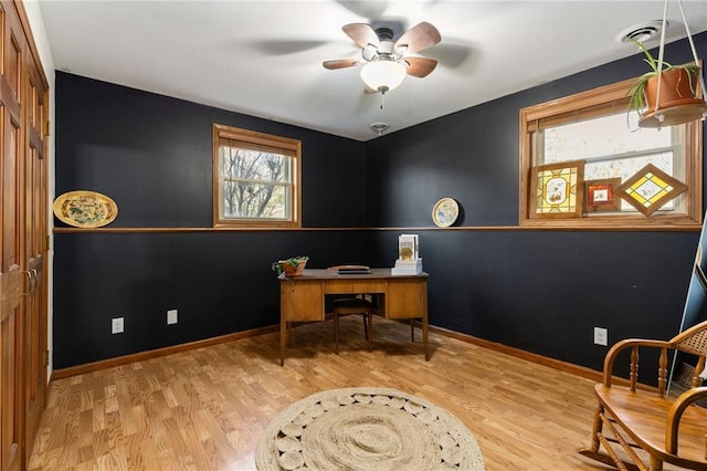 home office with visible vents, plenty of natural light, wood finished floors, and a ceiling fan