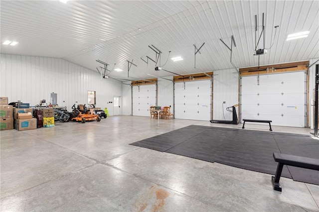 garage featuring electric panel, metal wall, and a garage door opener