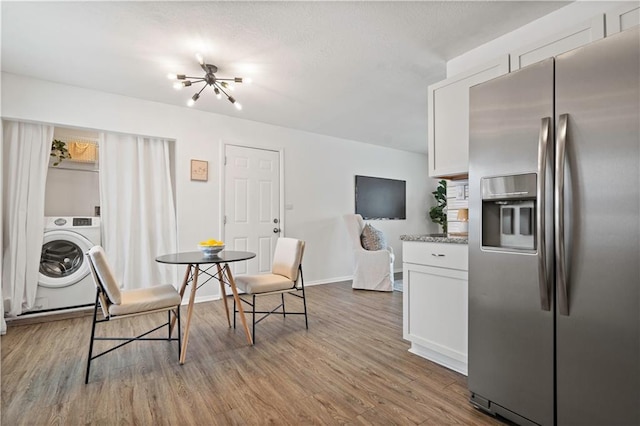 kitchen featuring washer / dryer, white cabinets, stainless steel refrigerator with ice dispenser, and wood finished floors