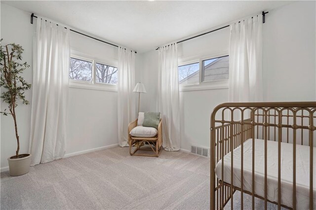 carpeted bedroom with visible vents, a crib, and baseboards